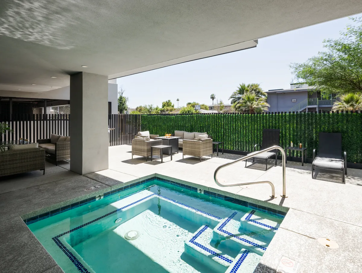 An outdoor hot tub with adjacent seating nestled among tasteful landscaping. The space exudes tranquility, inviting guests to unwind in the bubbling water or relax in a peaceful outdoor setting.